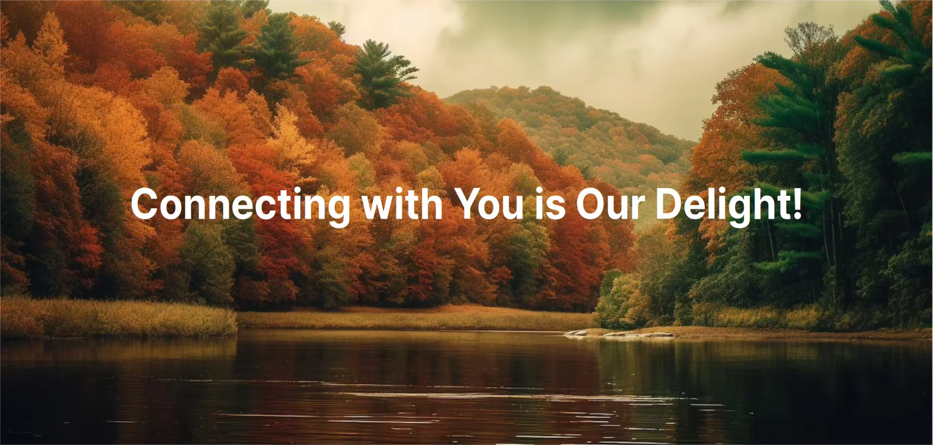 A beautiful picture of nature - a lake surrounded by trees that are green, yellow, orange and red with the text "Connecting with You is Our Delight!" on the image. The weather is cool and cloudy.