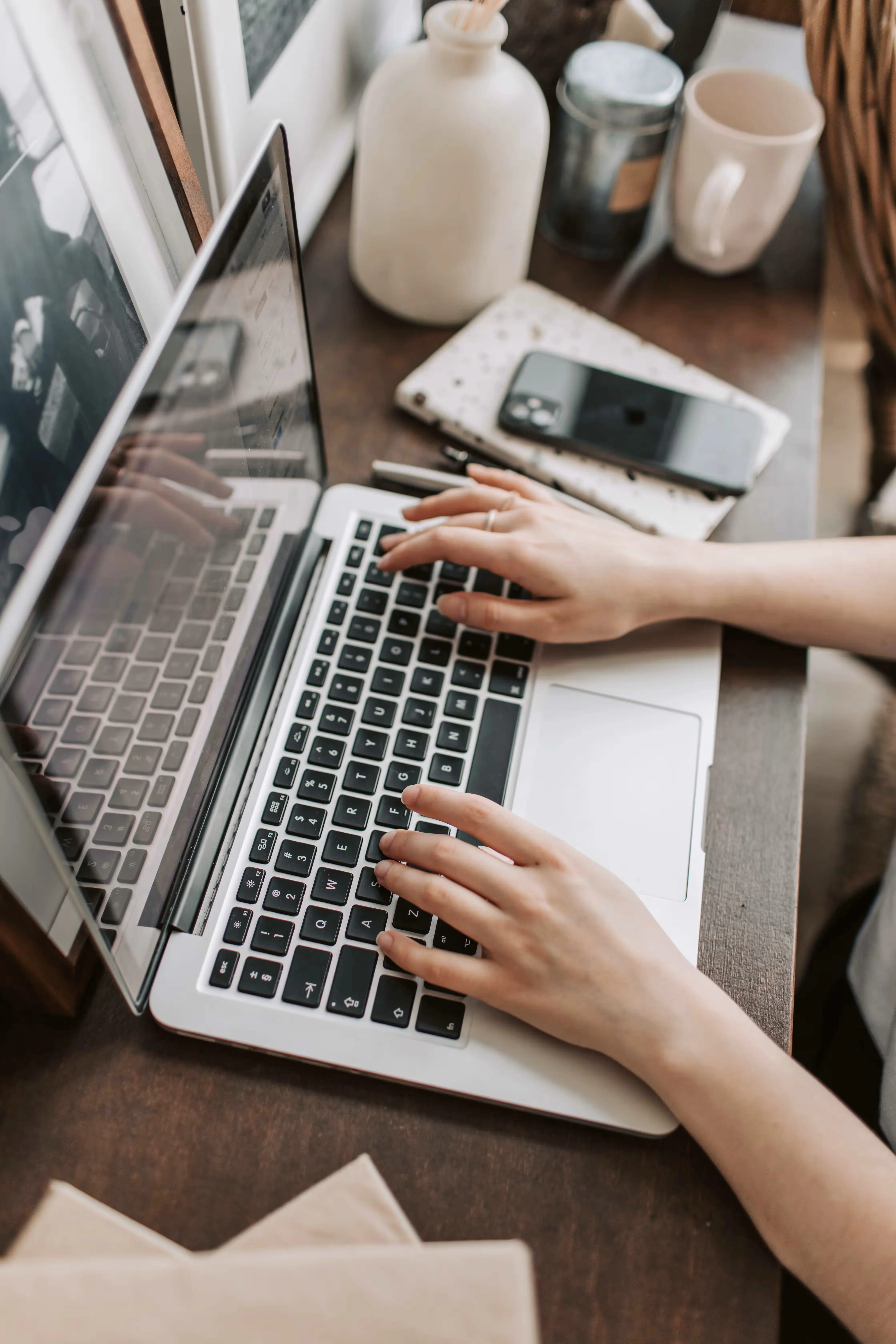 A woman working on a Macbook on a wooden desk