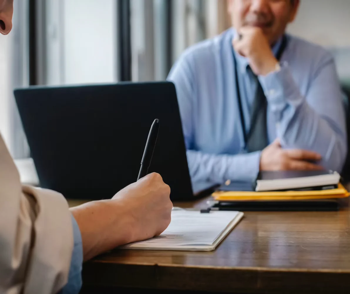 A woman talking to a man and noting down something on a writing pad with a pen